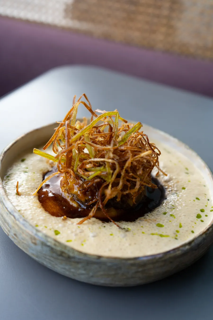 Crispy leek over a dark sauce and cream